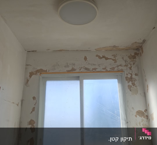 חדר עם קירות מתקלפים ודלי צהוב על הרצפה